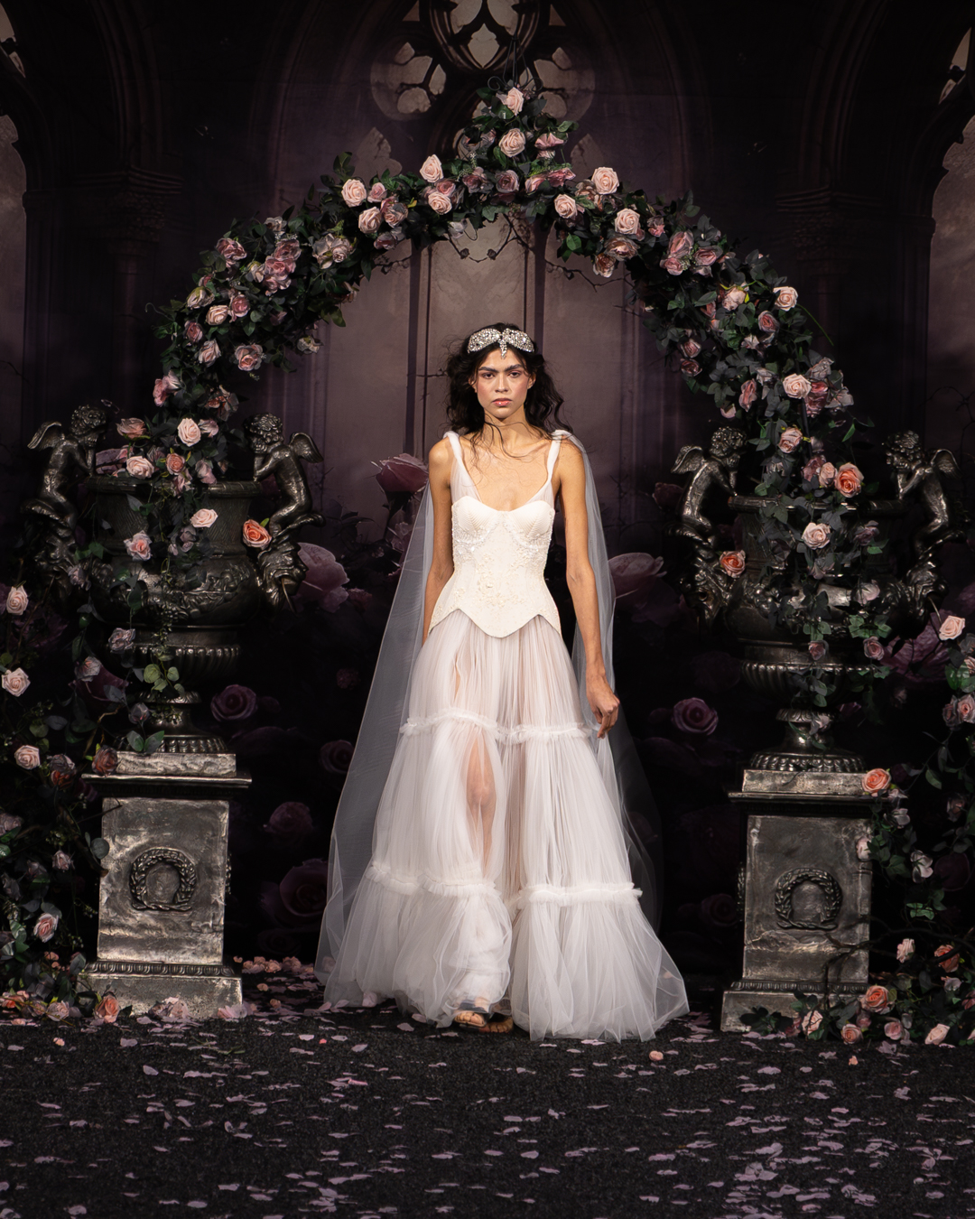 Model in a white corset and tiered tulle skirt with a veil