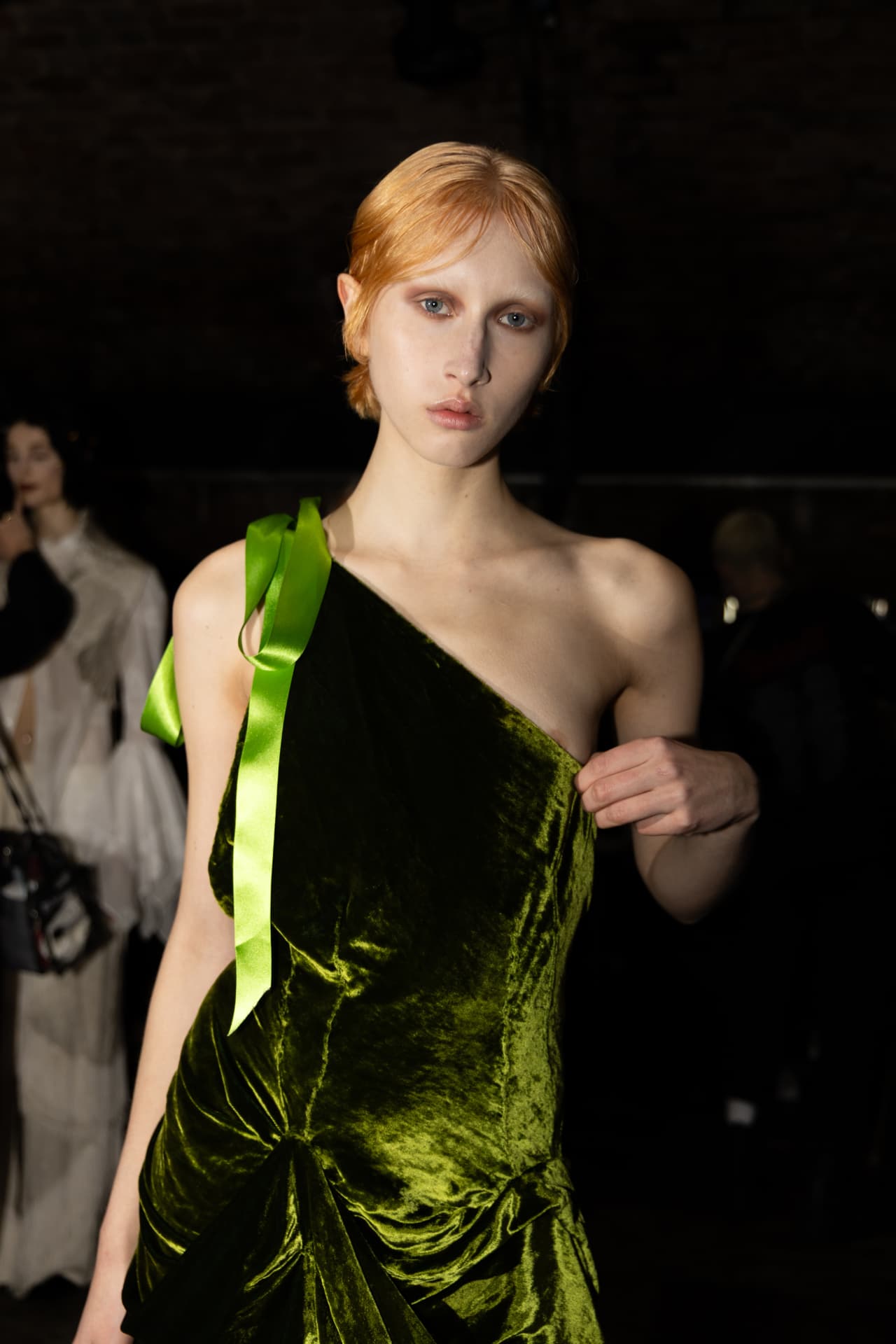 Model in green velvet dress with satin ribbon backstage