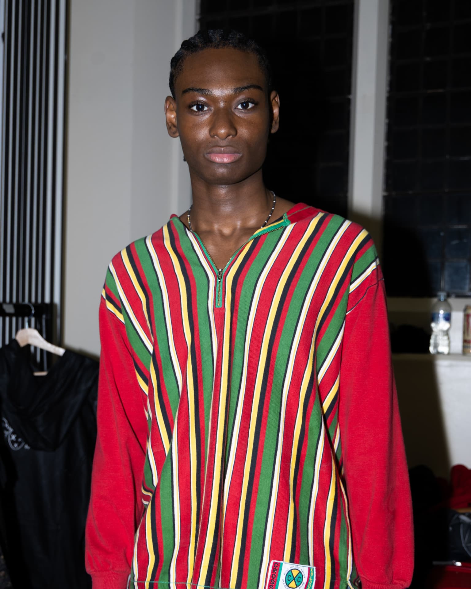 Model in red, green and yellow striped zip-up top backstage