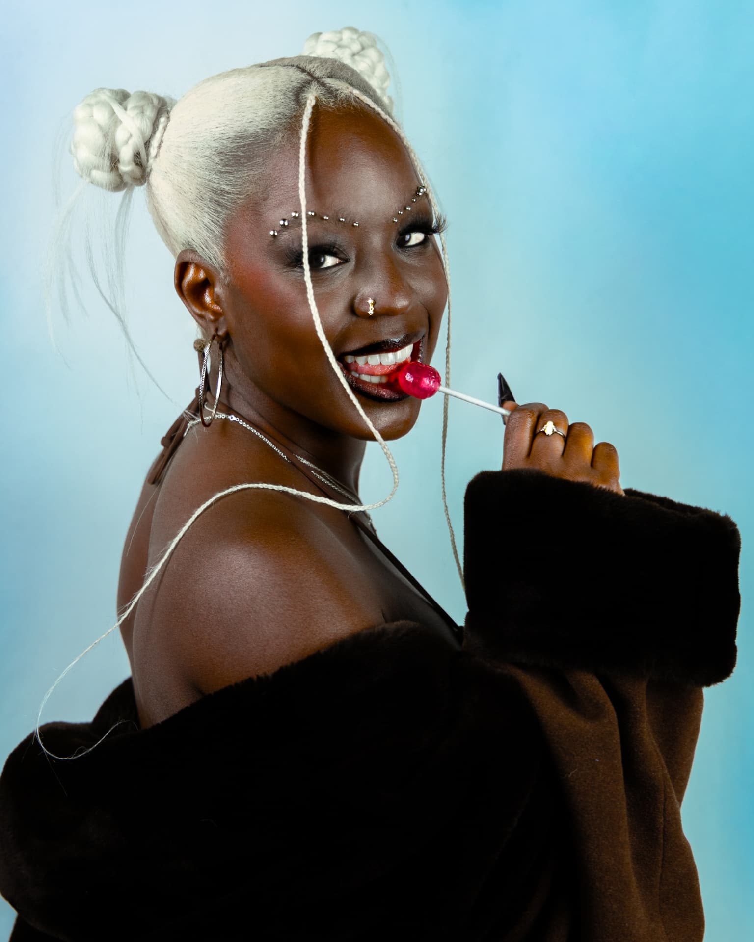 Model smiling with a pink lollipop in brown fur