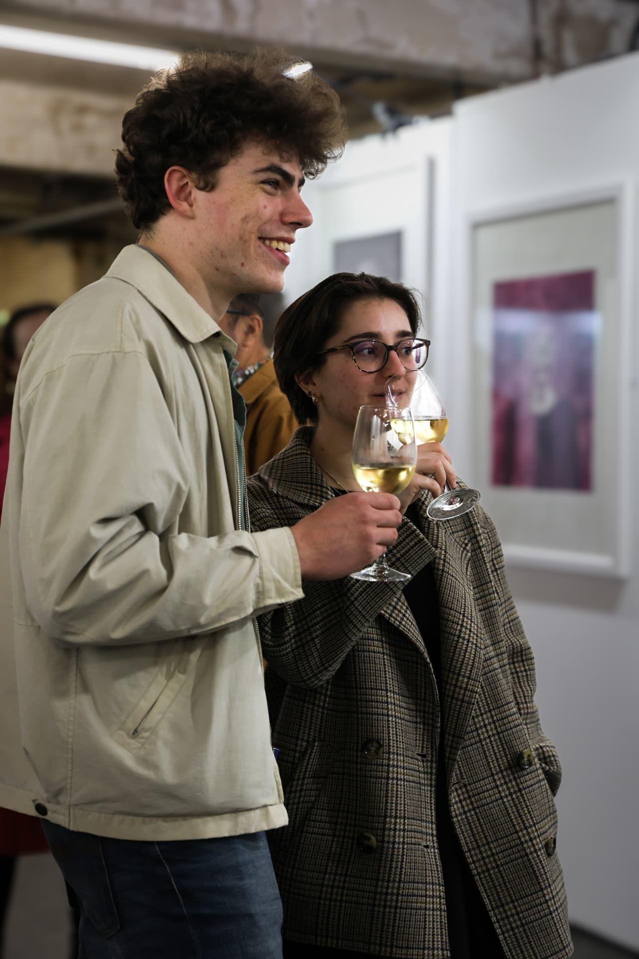 Two guests with wine glasses smiling at the exhibition opening
