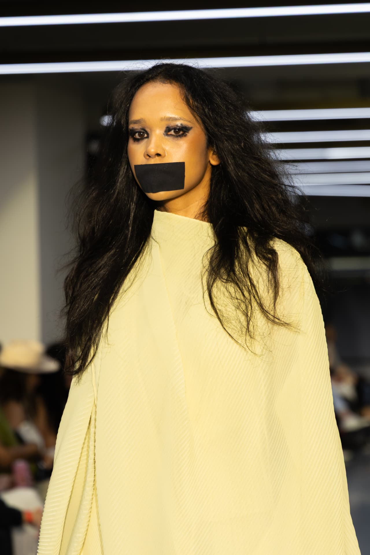 Model in a pale yellow pleated cape
