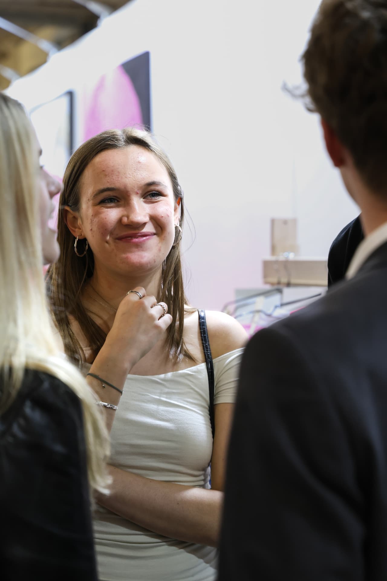 Guest smiling in conversation by a pink canvas