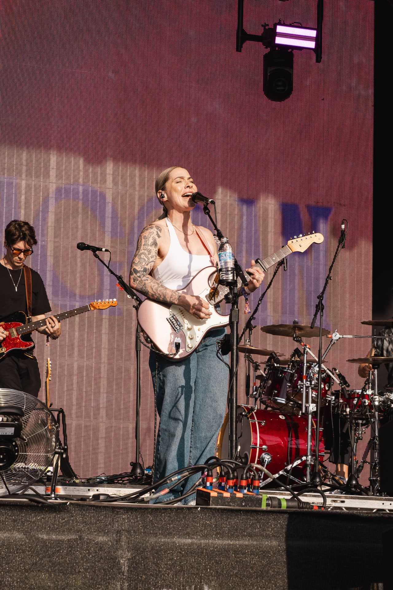 Singer with pink guitar against a magenta LED wall