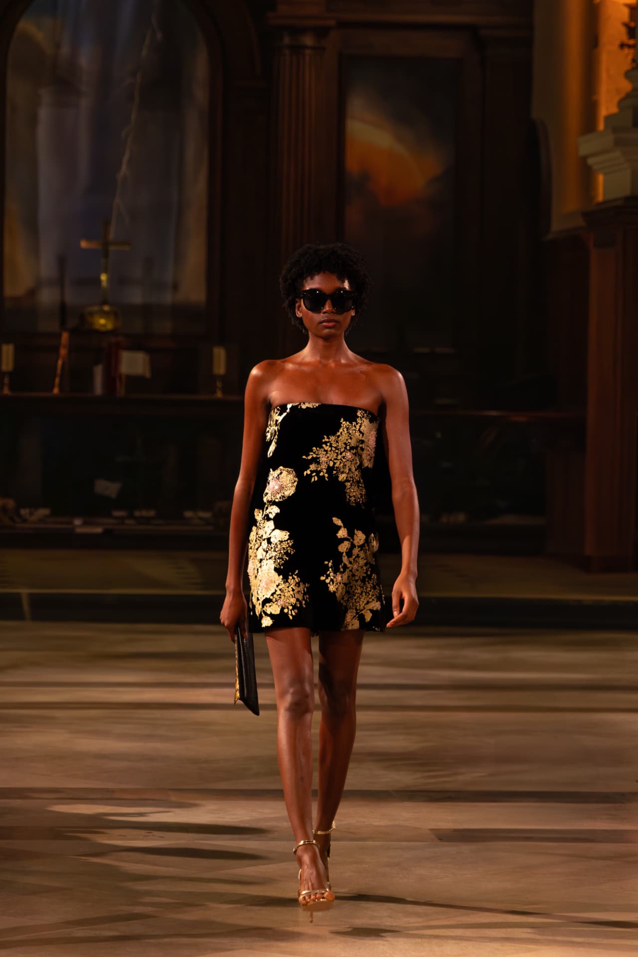 Model in a black and gold floral strapless mini dress