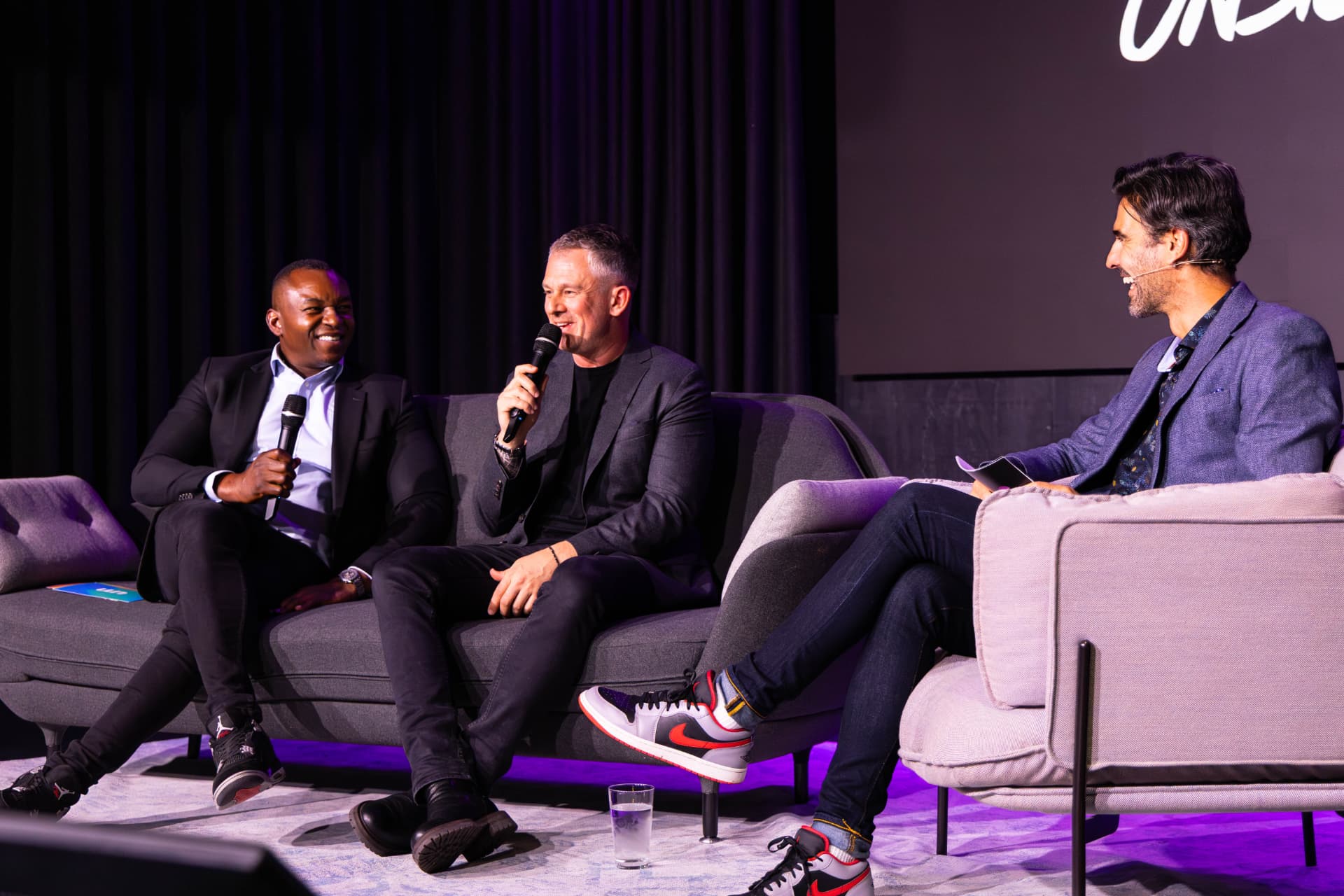 Panel discussion in progress under purple stage lighting