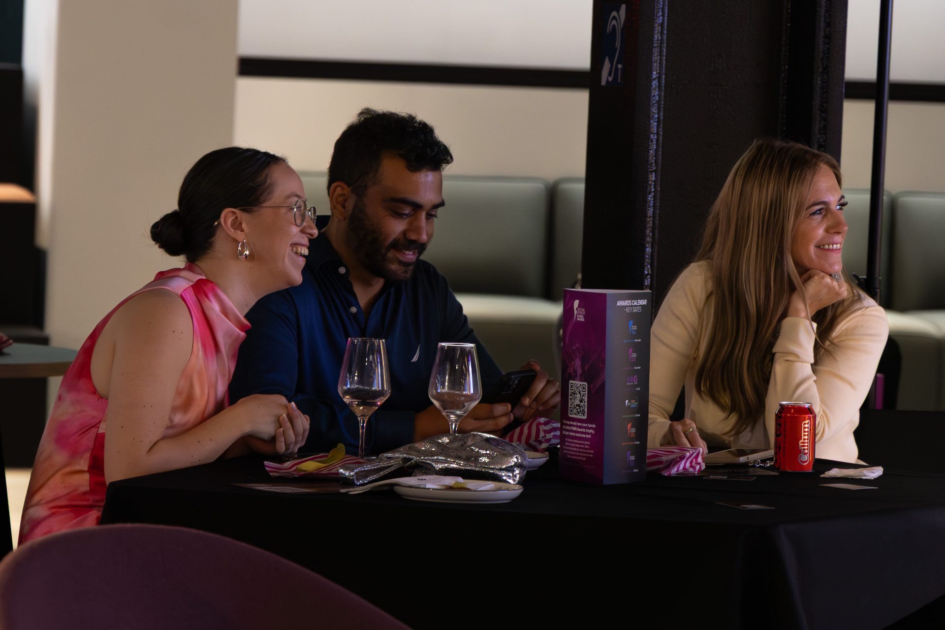 Three guests laughing together at a table during the ceremony