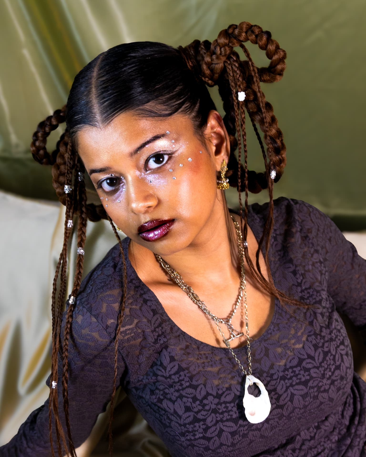 Seated portrait with looped braids and layered chains