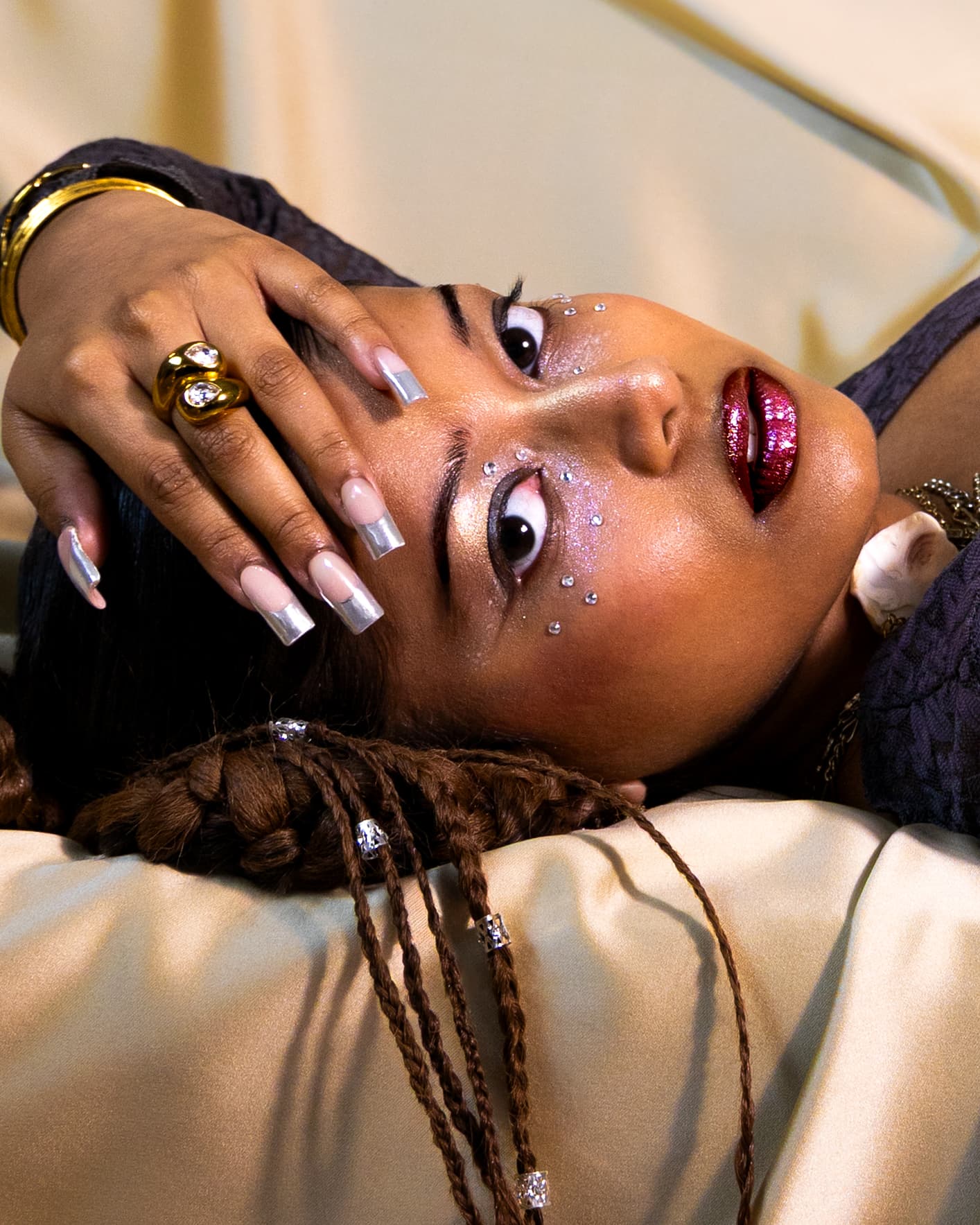 Close crop of jewelled eye makeup and chrome nails
