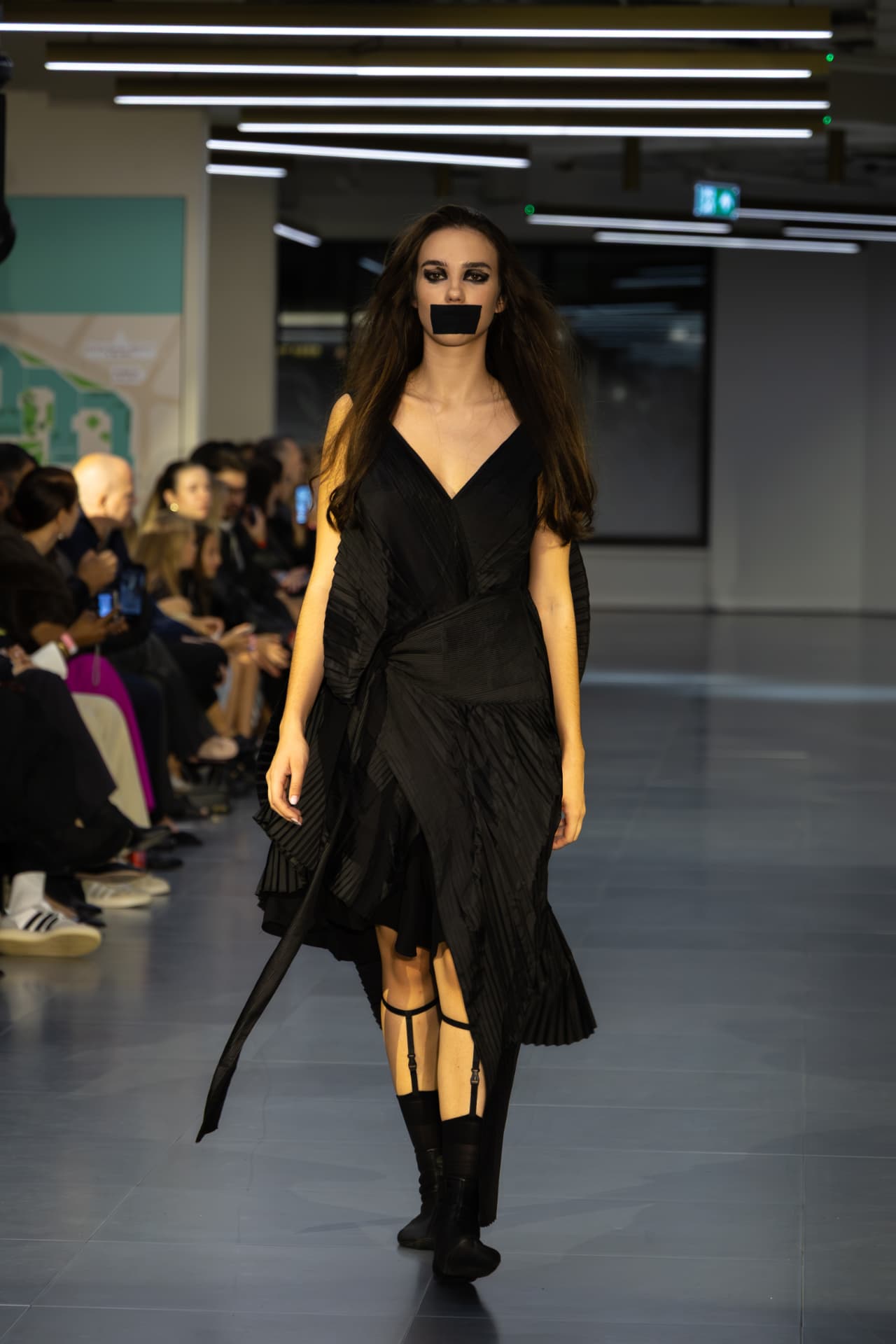 Model in a black pleated wrap dress on the runway