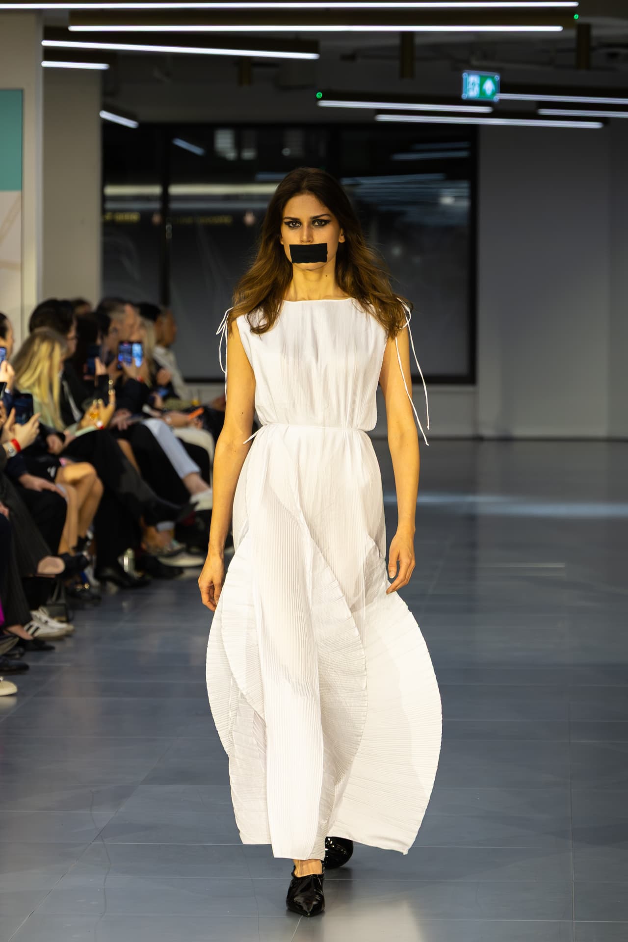Model in a white pleated sleeveless gown
