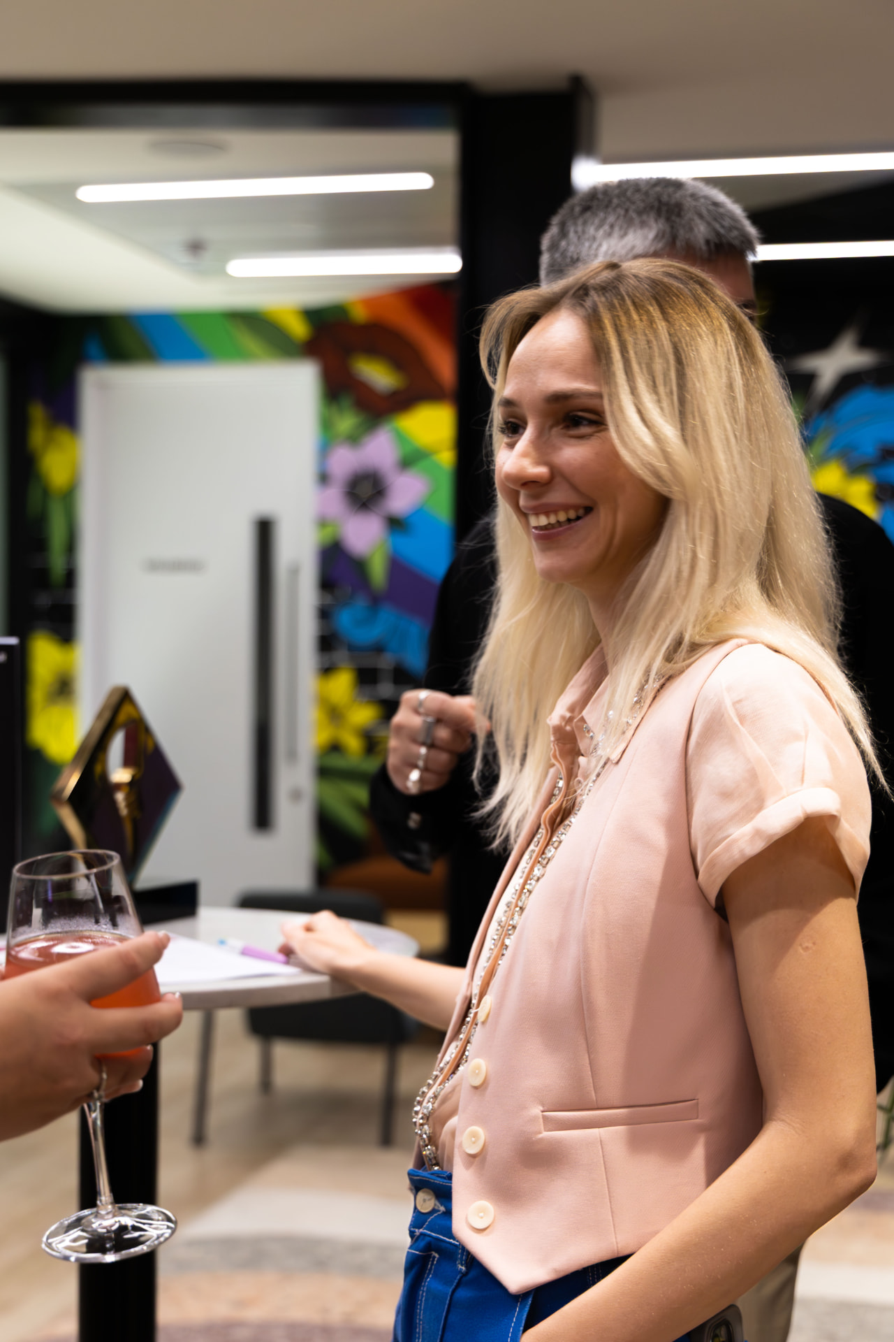 Guest in a pink blazer smiling during the drinks reception