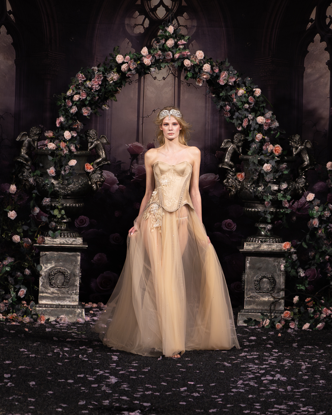 Model in a champagne corset and tulle gown at the rose arch