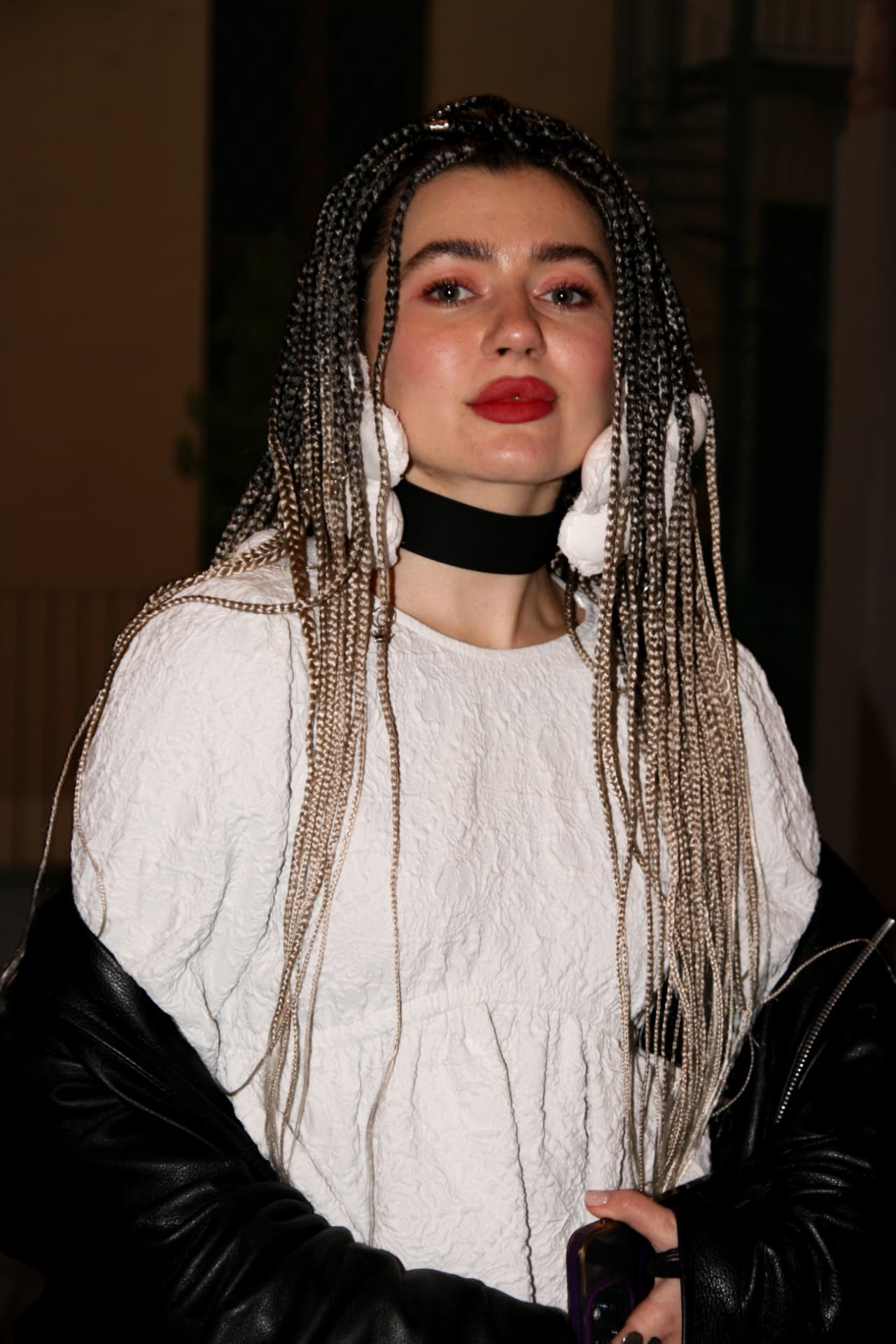 Guest with long braids in a textured white top and black choker