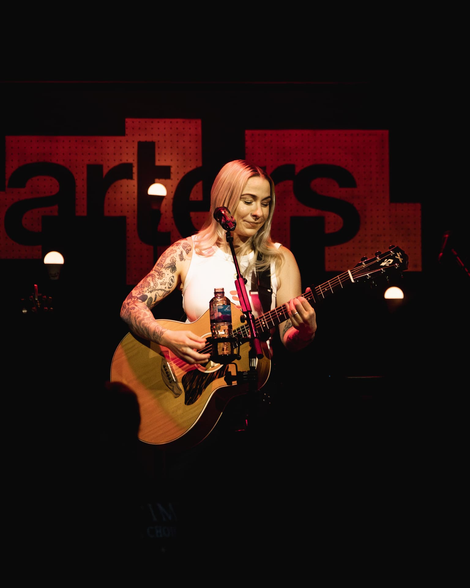 Playing guitar in front of the red Quarters backdrop