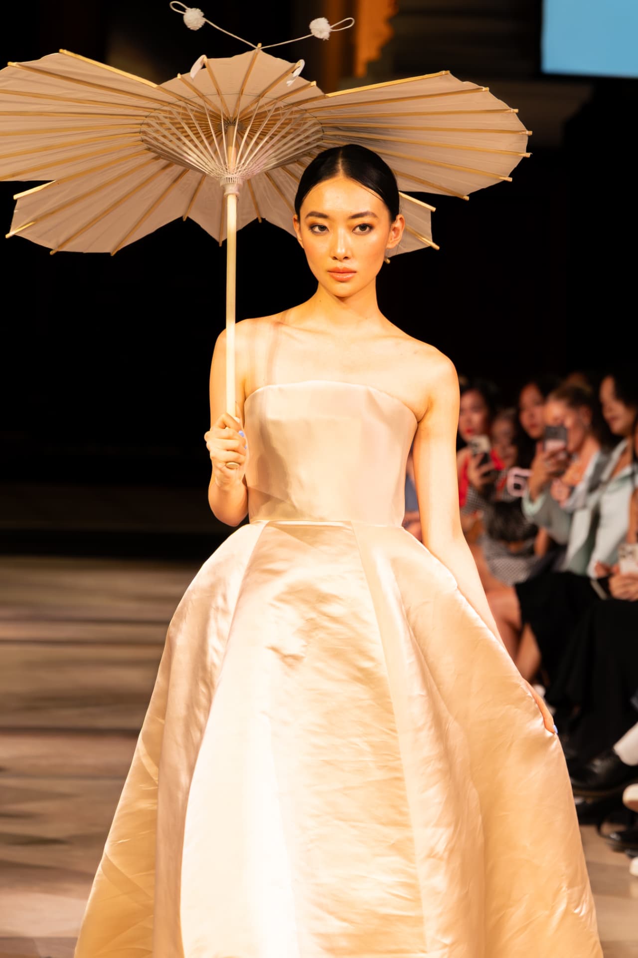 Model in a cream silk gown holding a paper parasol