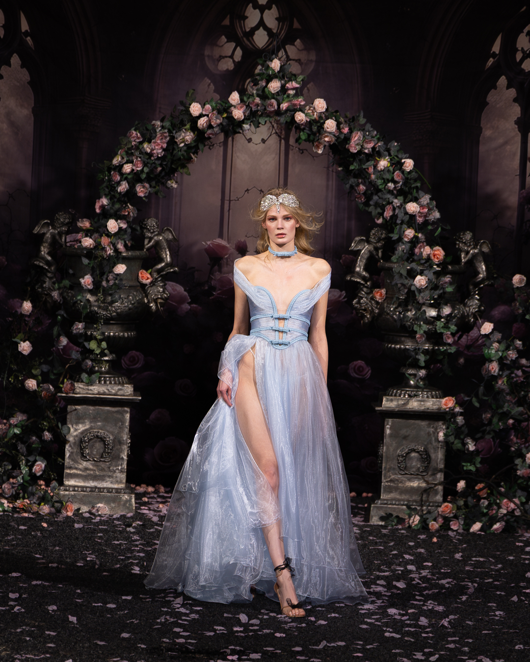 Model in a pale blue organza gown beneath a rose arch