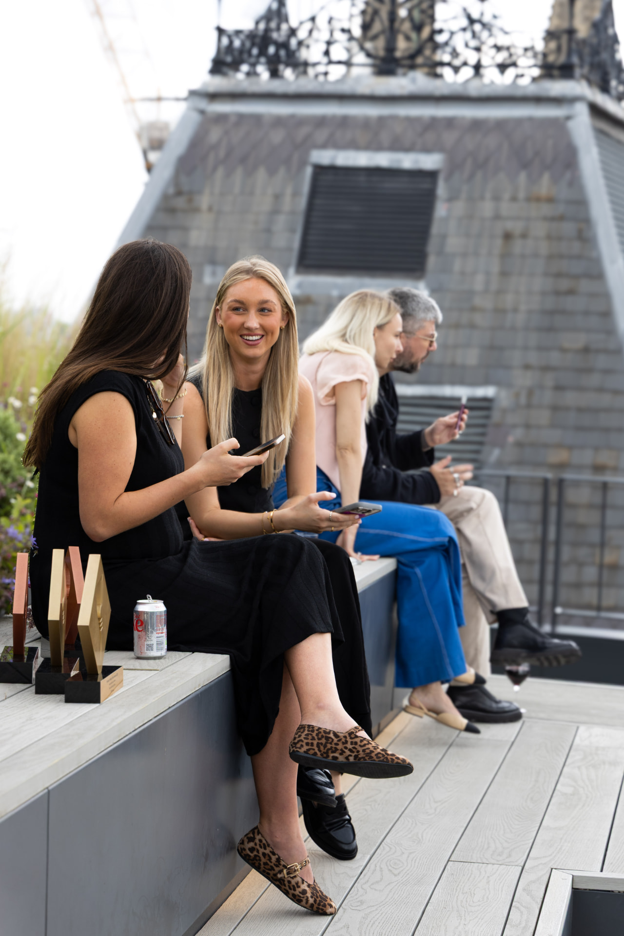 Guests chatting on the rooftop terrace with awards trophies beside them