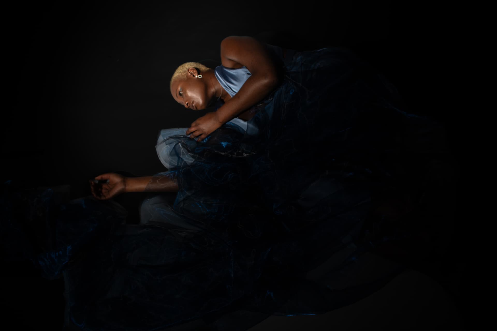 Model curled forward in a sweeping blue gown