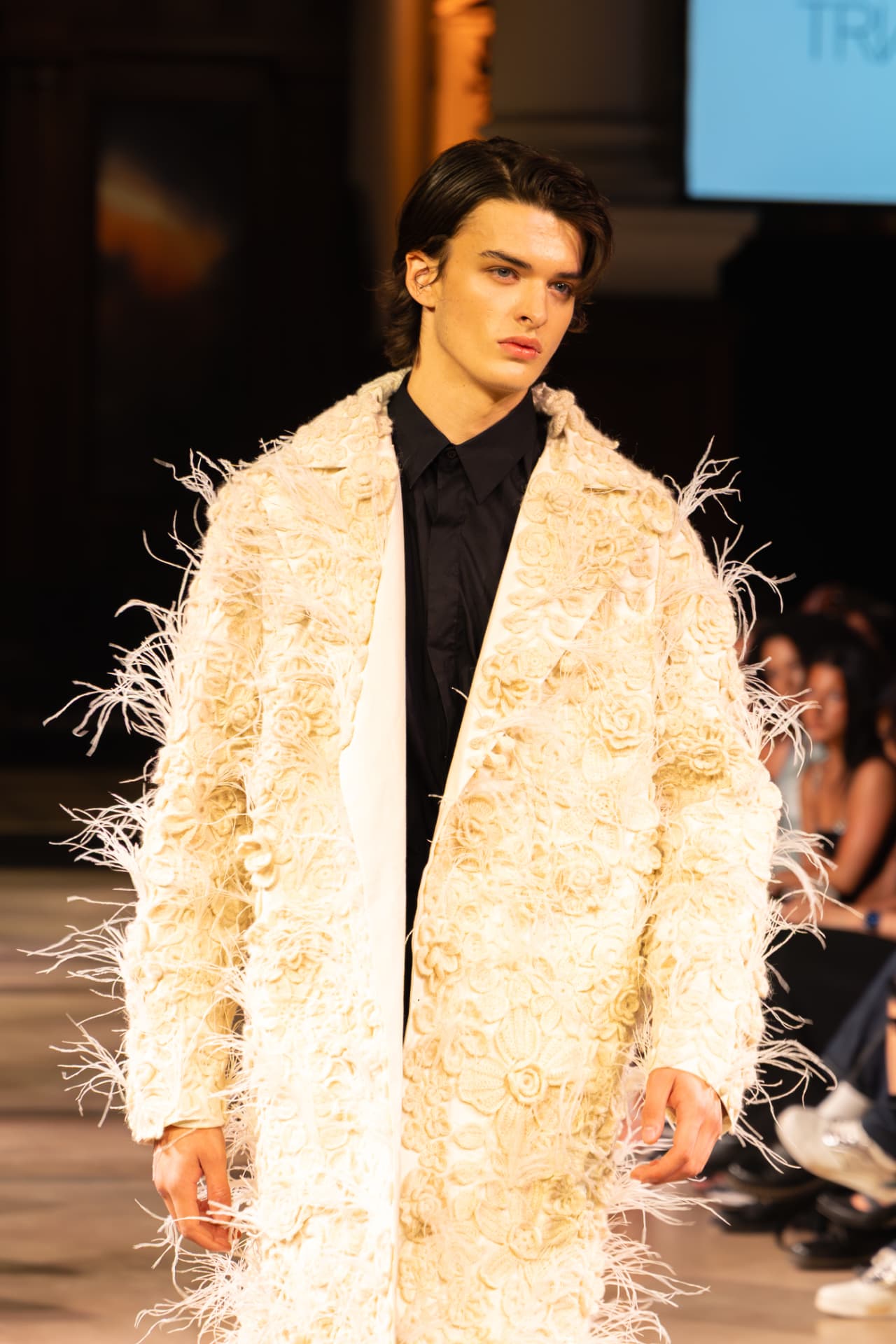 Model in a cream feather-trimmed floral coat
