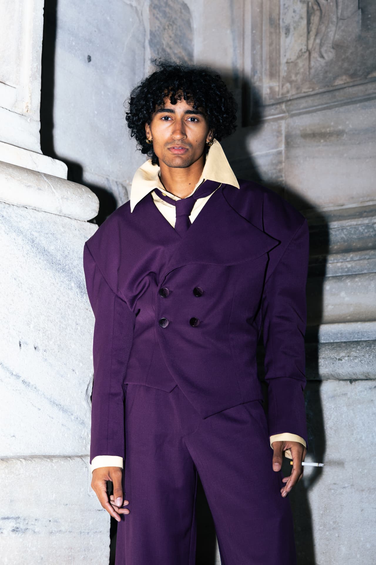 Model in a purple double-breasted suit against stone
