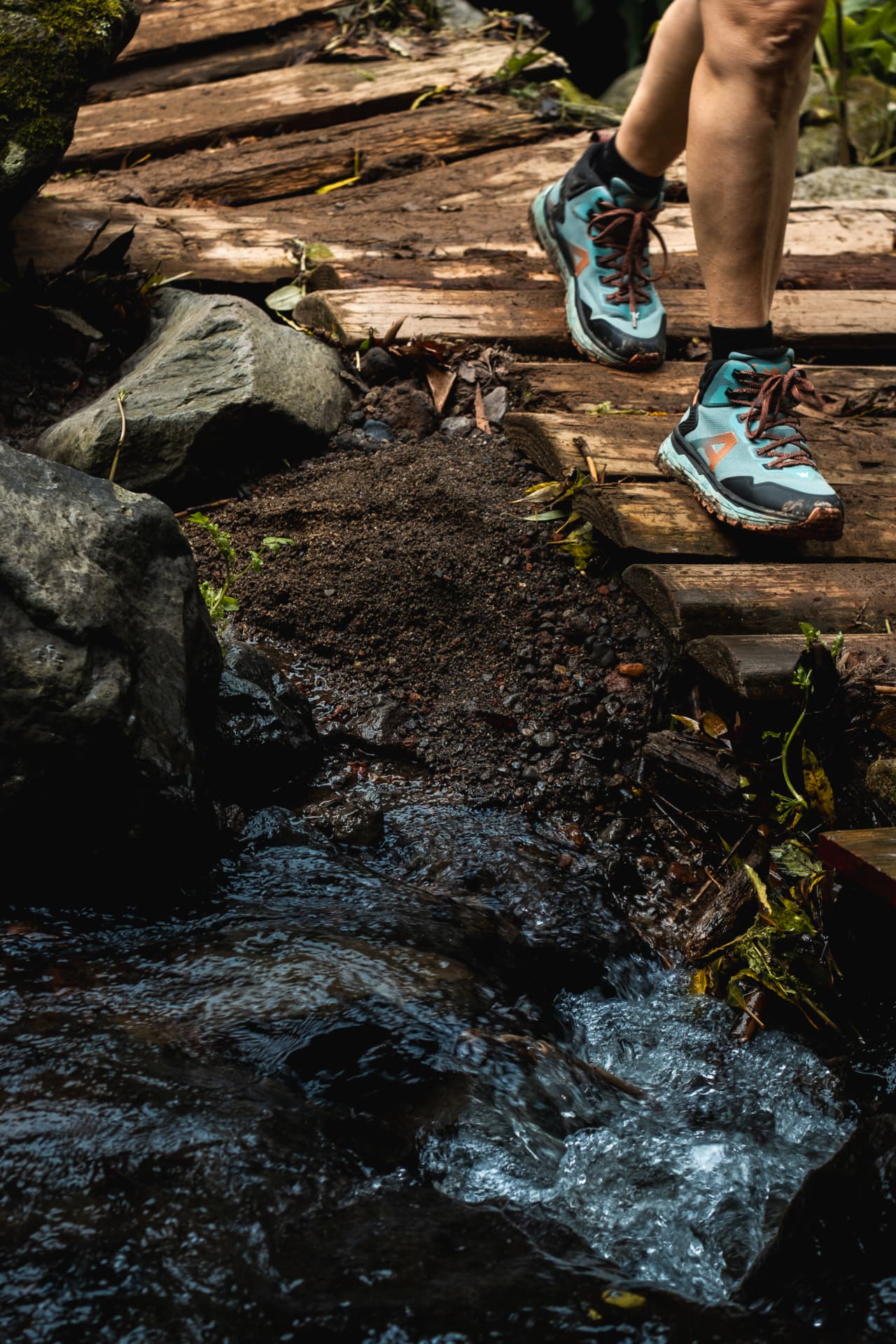 Hiker crossing a wooden footbridge over a forest stream