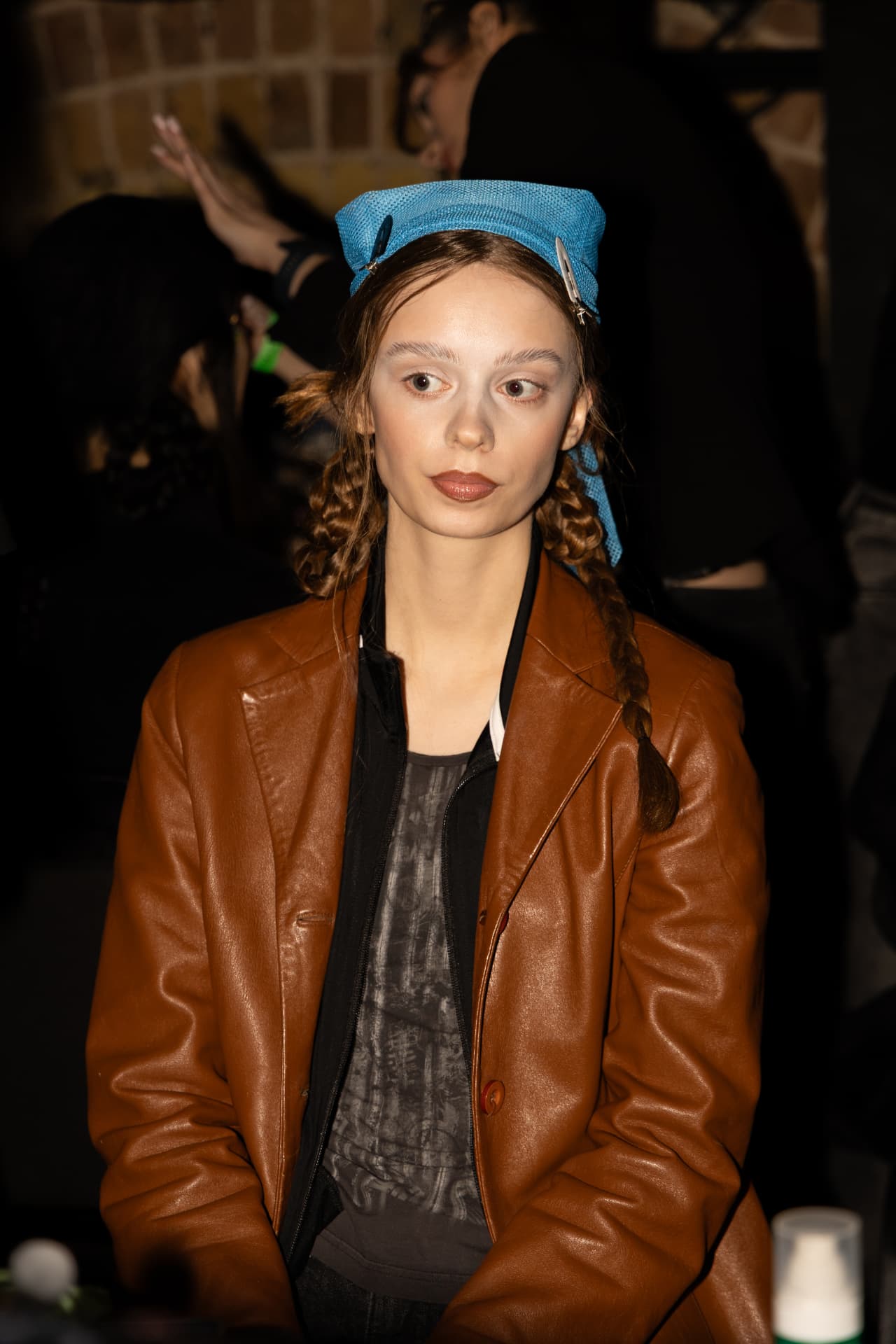 Model in tan leather jacket and blue headpiece