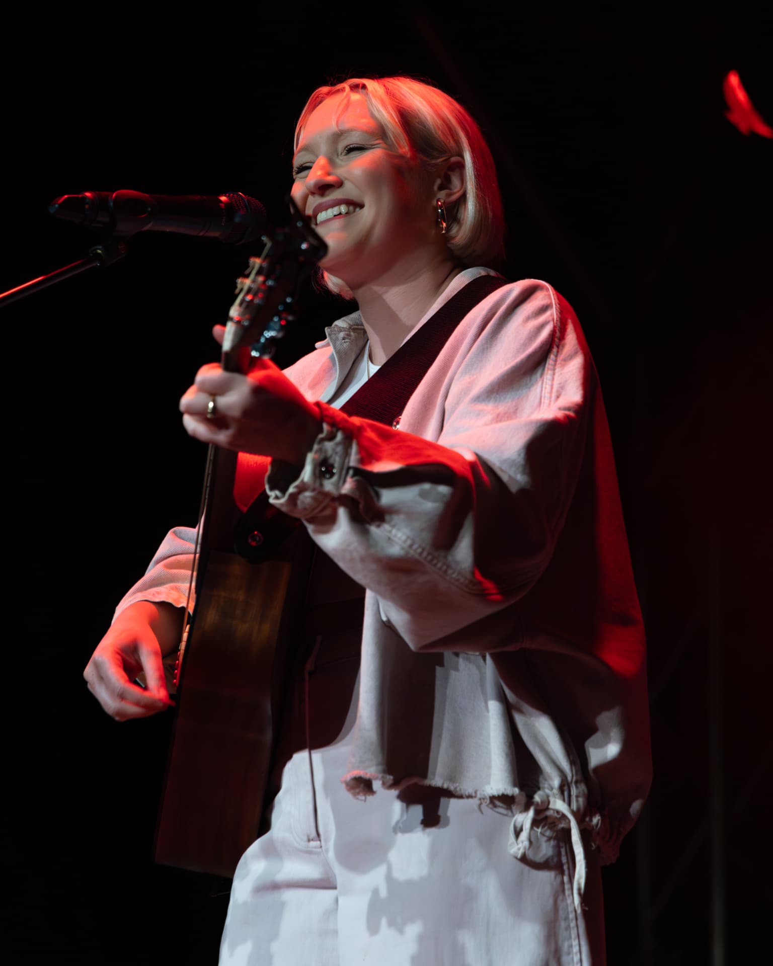 Molly Warburton smiling at the microphone in red light