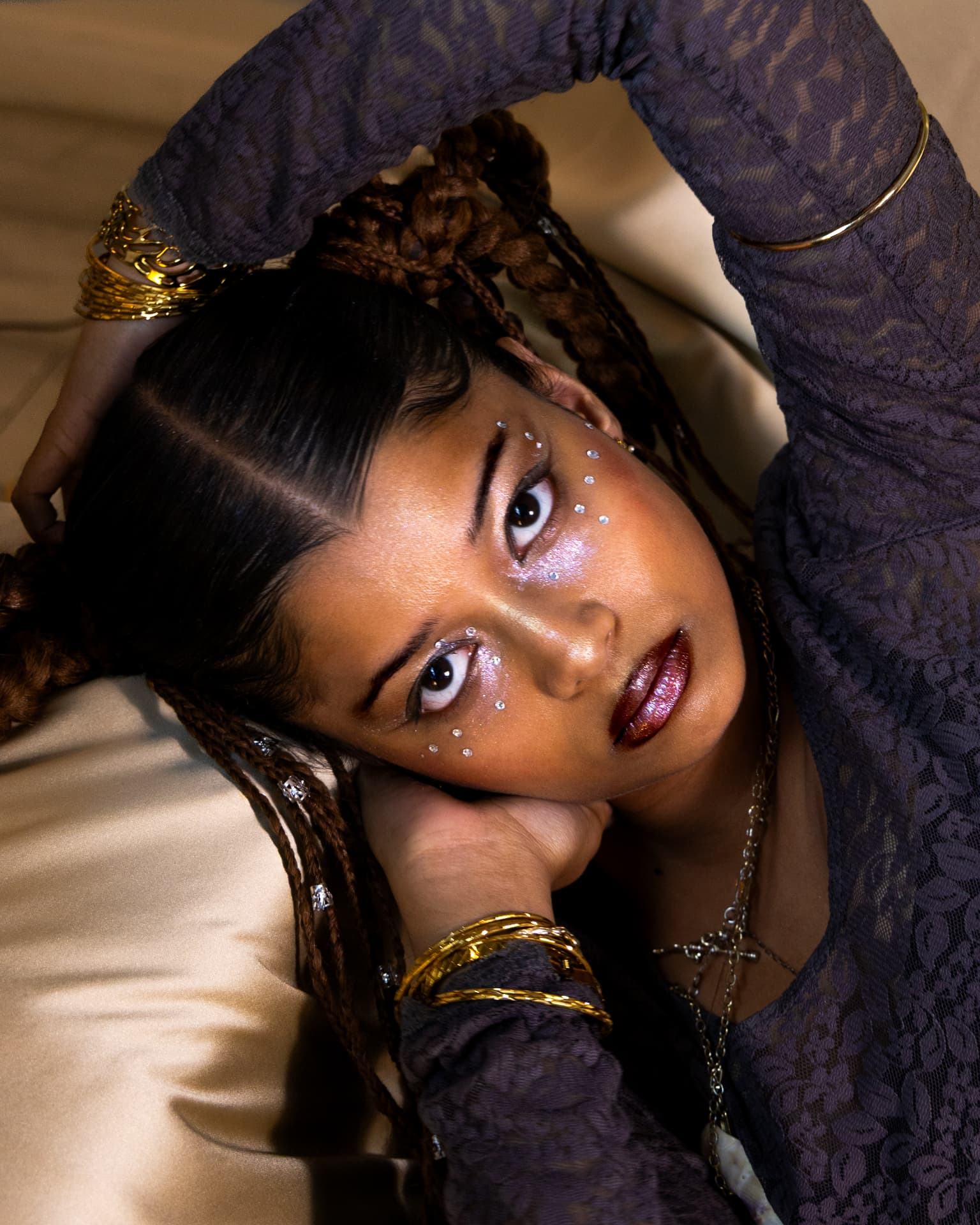 Model reclining on gold satin with jewelled makeup