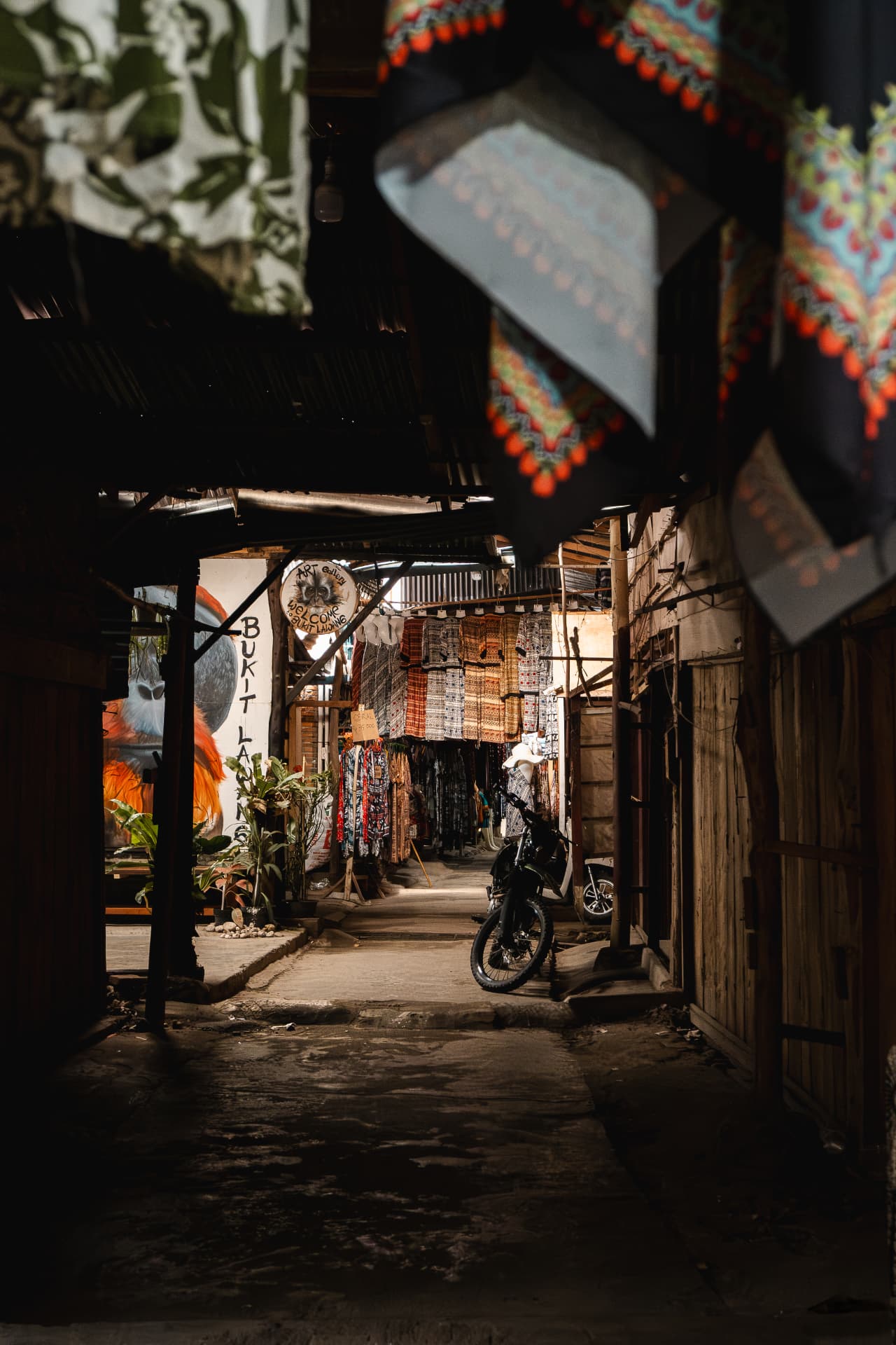 Narrow alley of a textile market with hanging fabrics and a parked bicycle