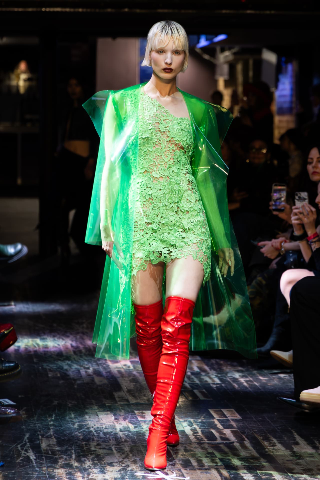 Model in green lace with a translucent green coat and red boots