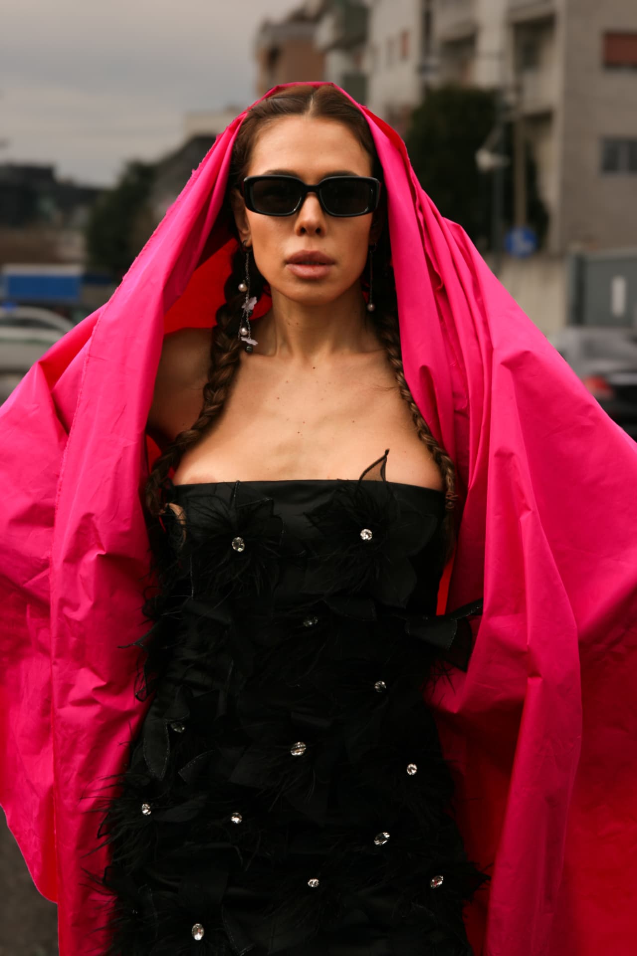 Guest draped in a hot pink cape over a black feathered dress
