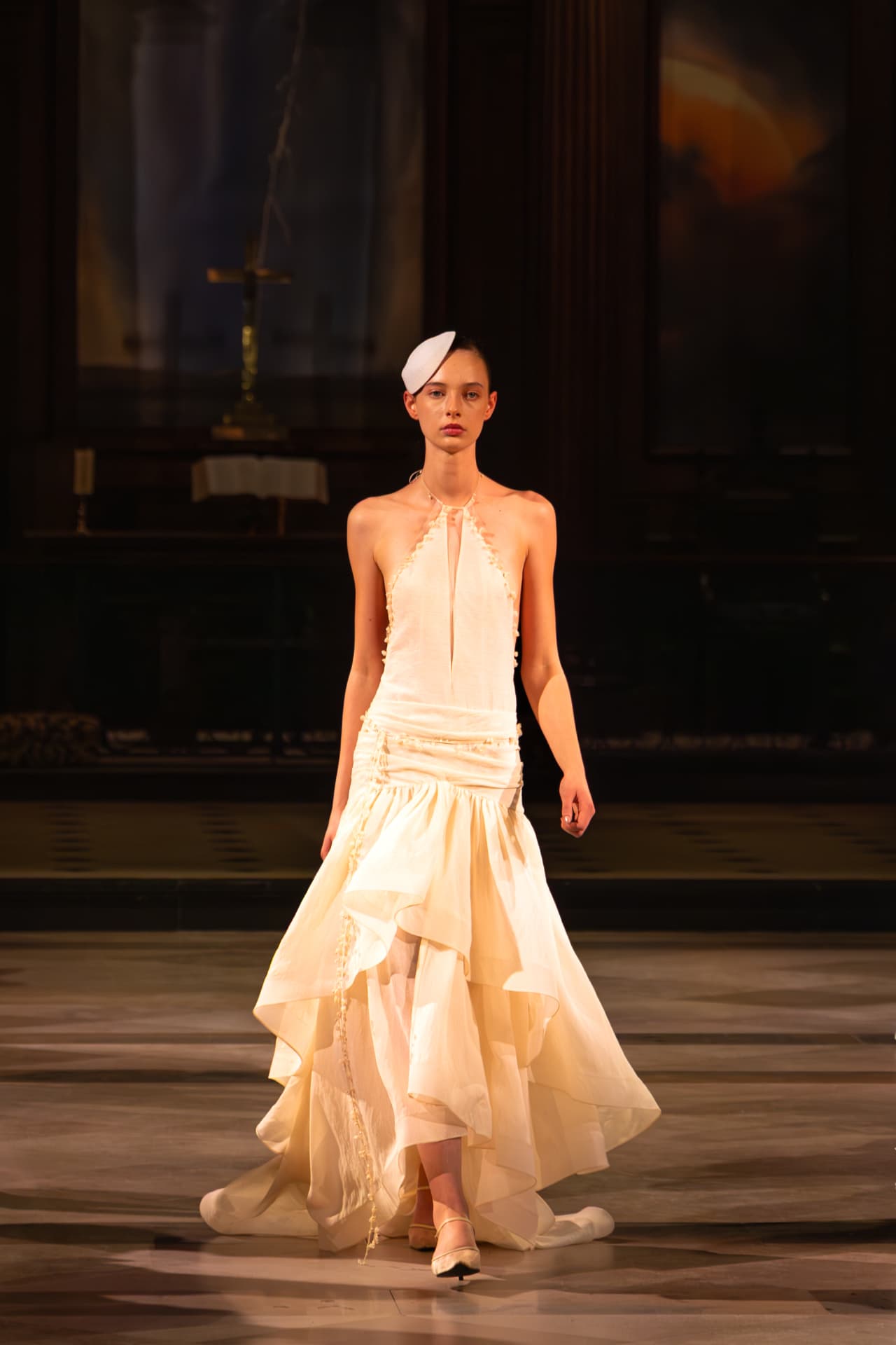 Model in a cream halter gown with a fluted hem