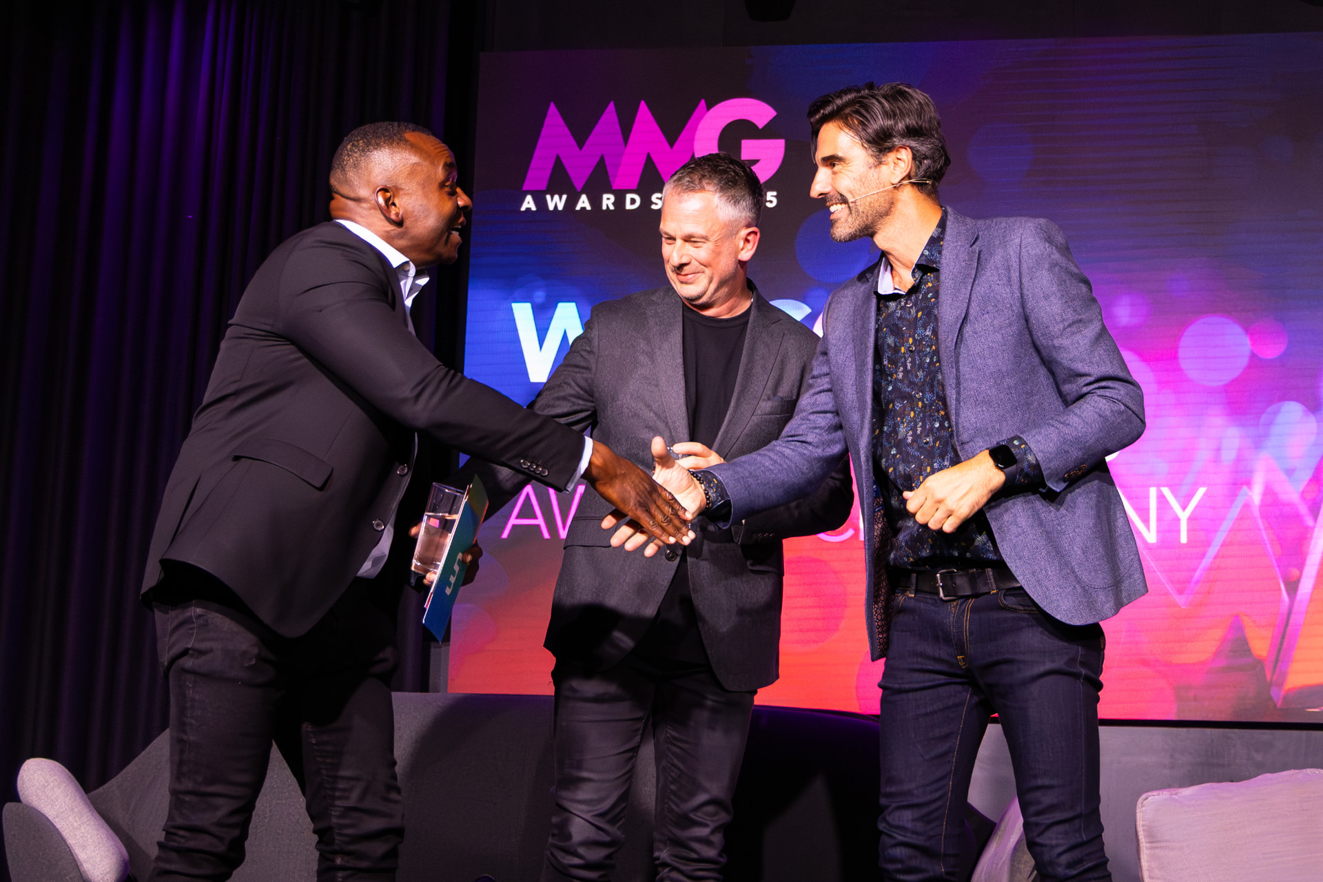 Award winner shaking hands on stage at the MNG Awards