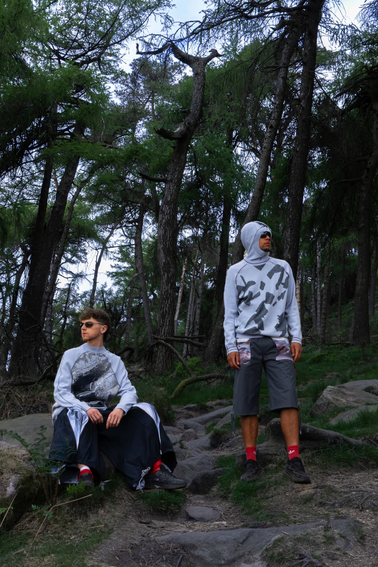 Two models in a pine forest wearing printed knitwear