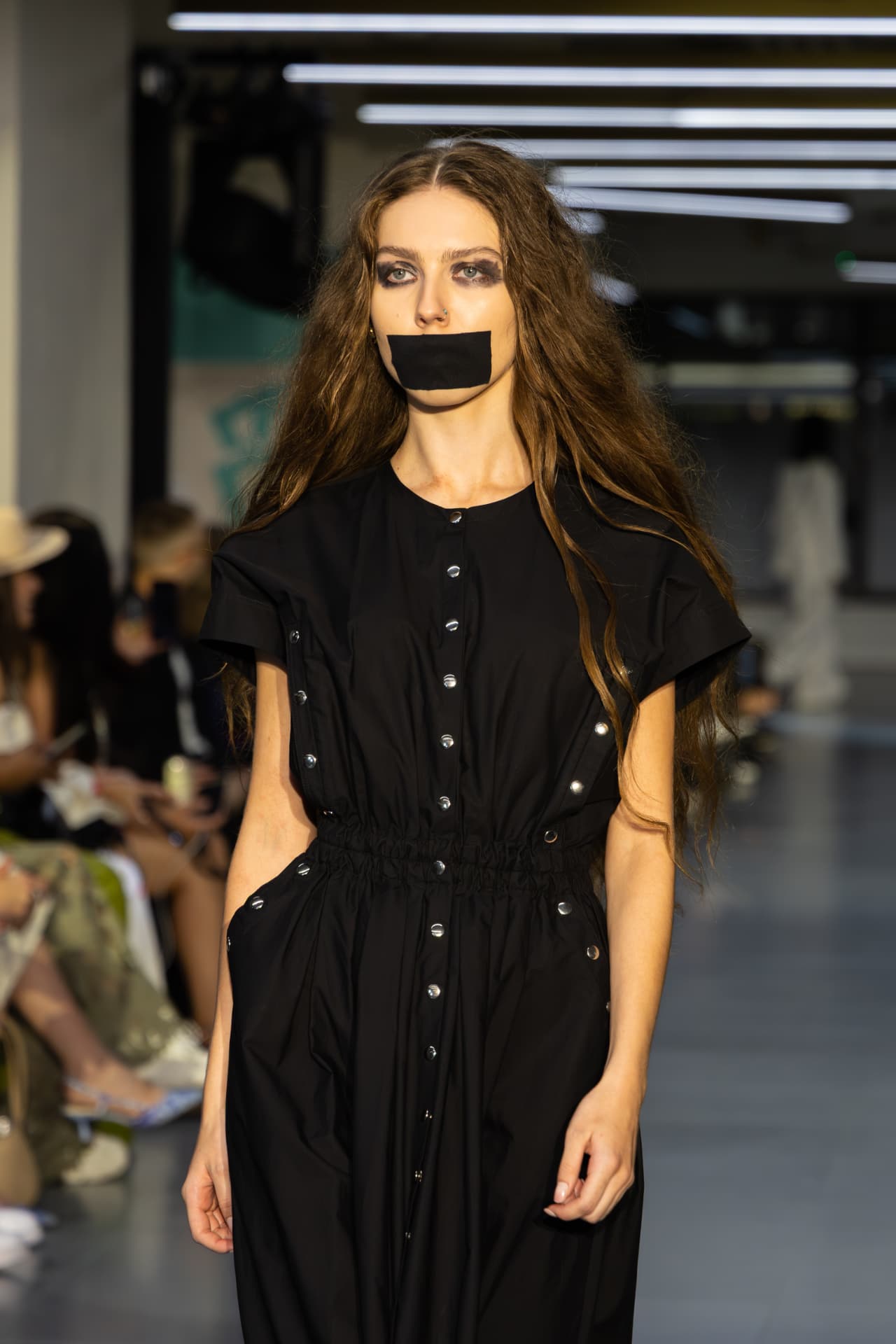 Model in a black snap-front utility dress