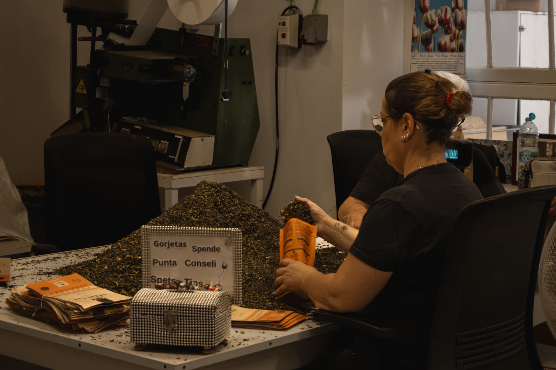 Woman packing tea into orange sachets at a factory
