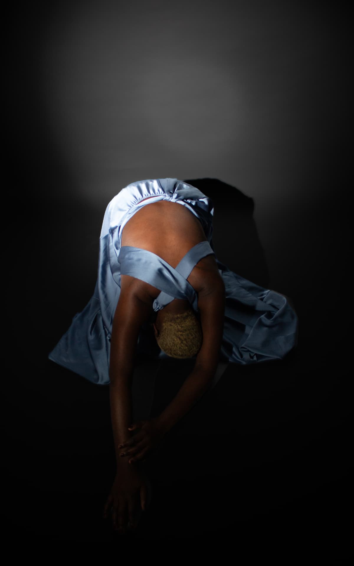 Overhead shot of a model bent forward in pale blue satin