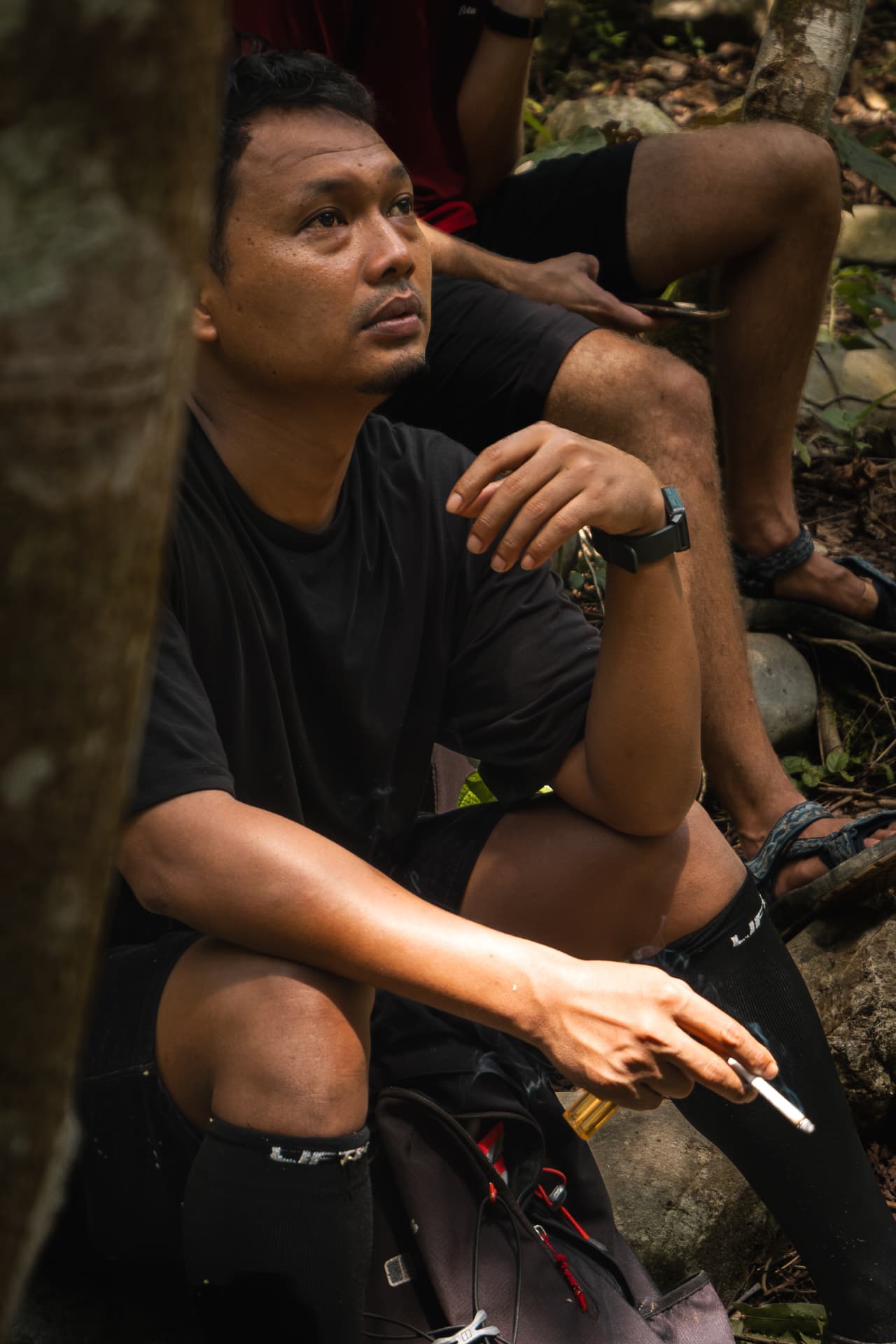 Man resting on rocks in dappled forest light