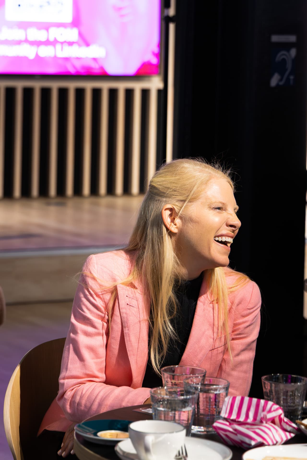 Guest laughing in a pink blazer at the table