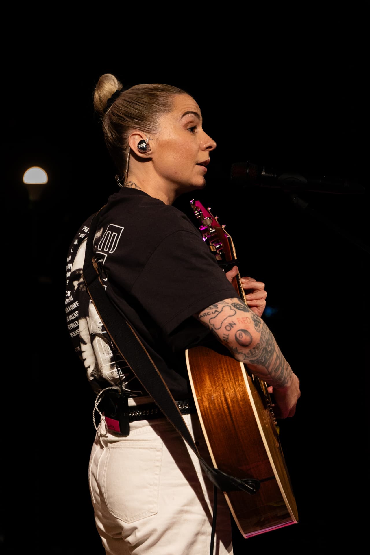 From behind, singing into the mic with guitar