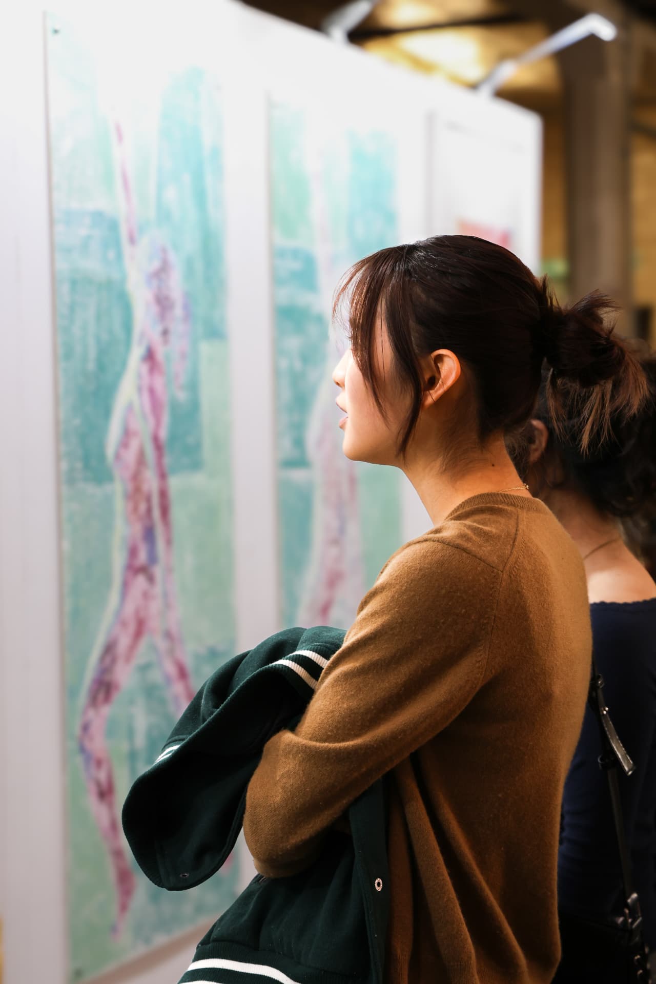 Visitor studying a large pastel figure painting