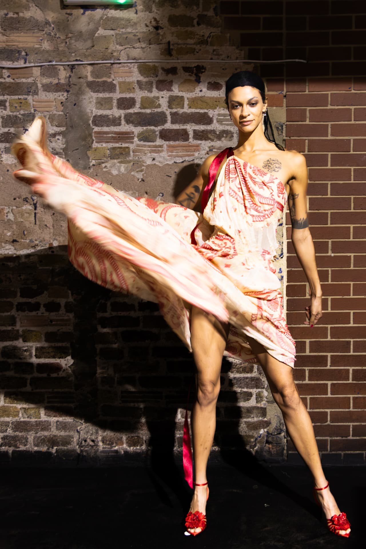 Model in red printed dress kicking the skirt out