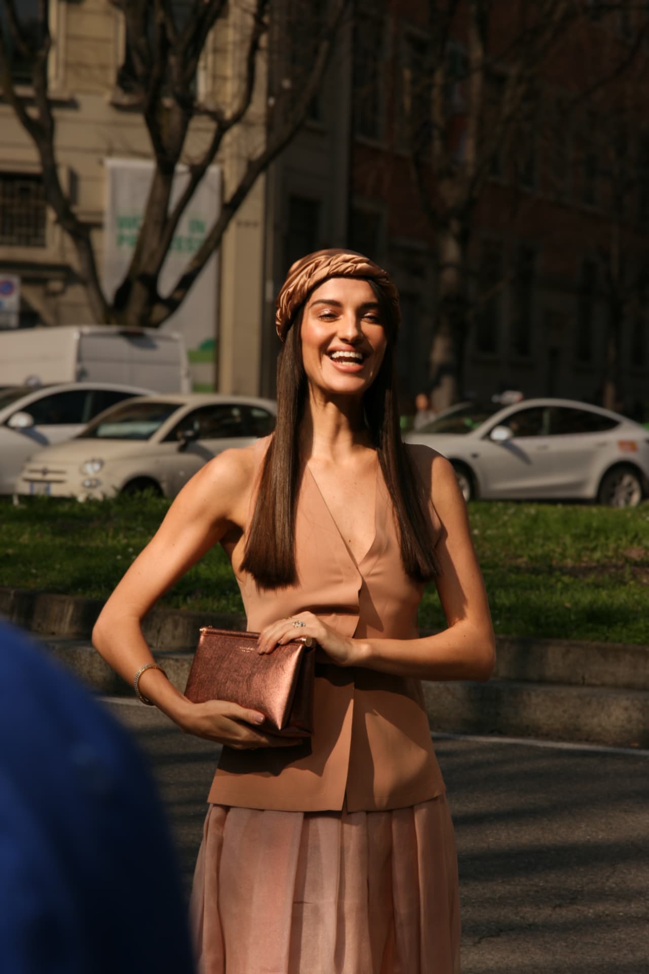 Guest laughing in a blush satin vest and pleated skirt