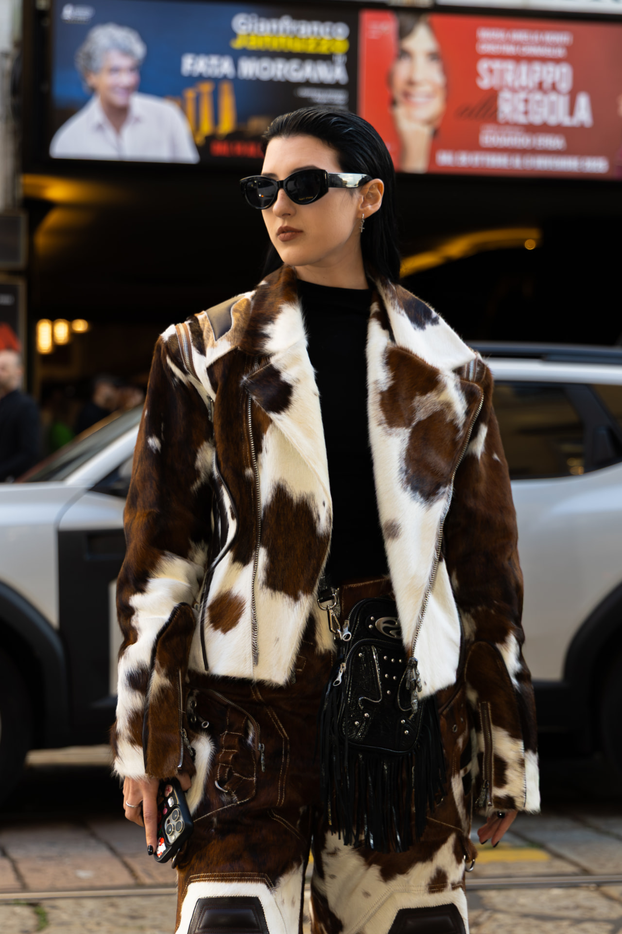 Street style portrait of a woman in a cow-print fur coat and sunglasses