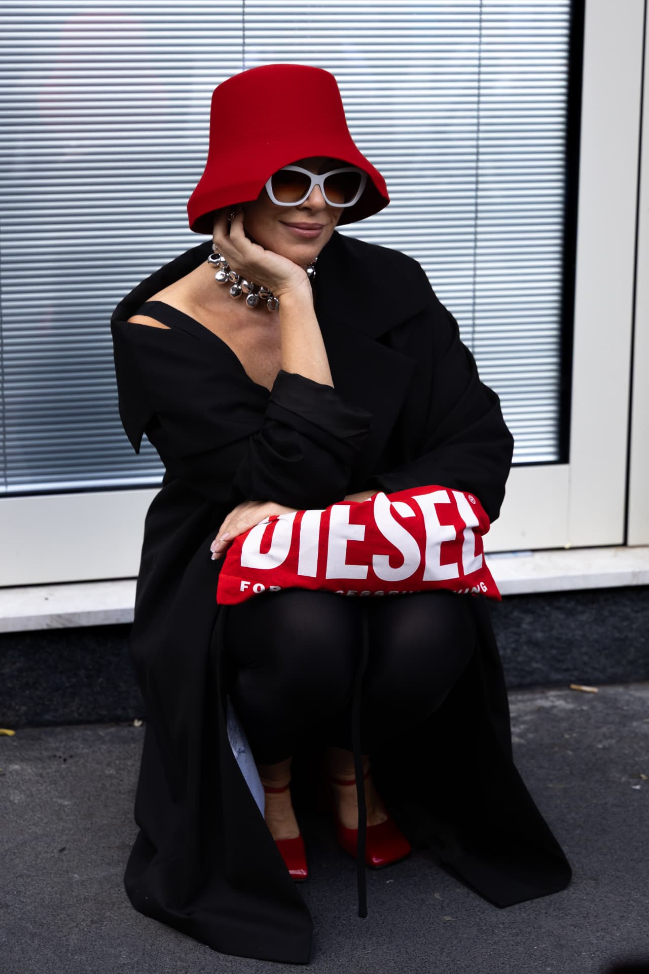 Guest in a red bucket hat and black coat with a red clutch