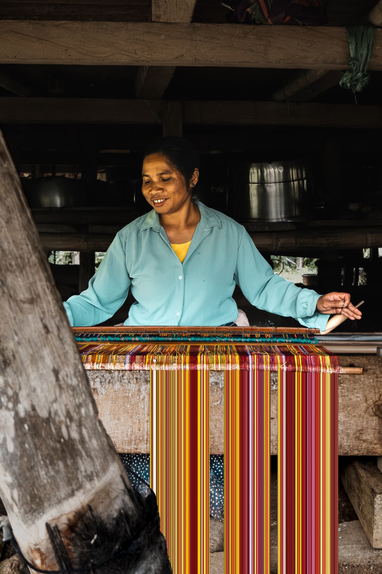Woman weaving bright striped cloth on a wooden loom