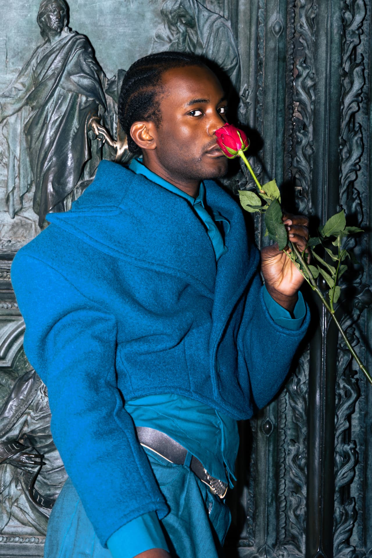 Model in a blue coat holding a red rose