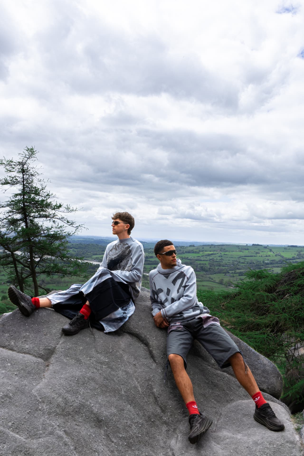 Two models seated on a rock above the countryside