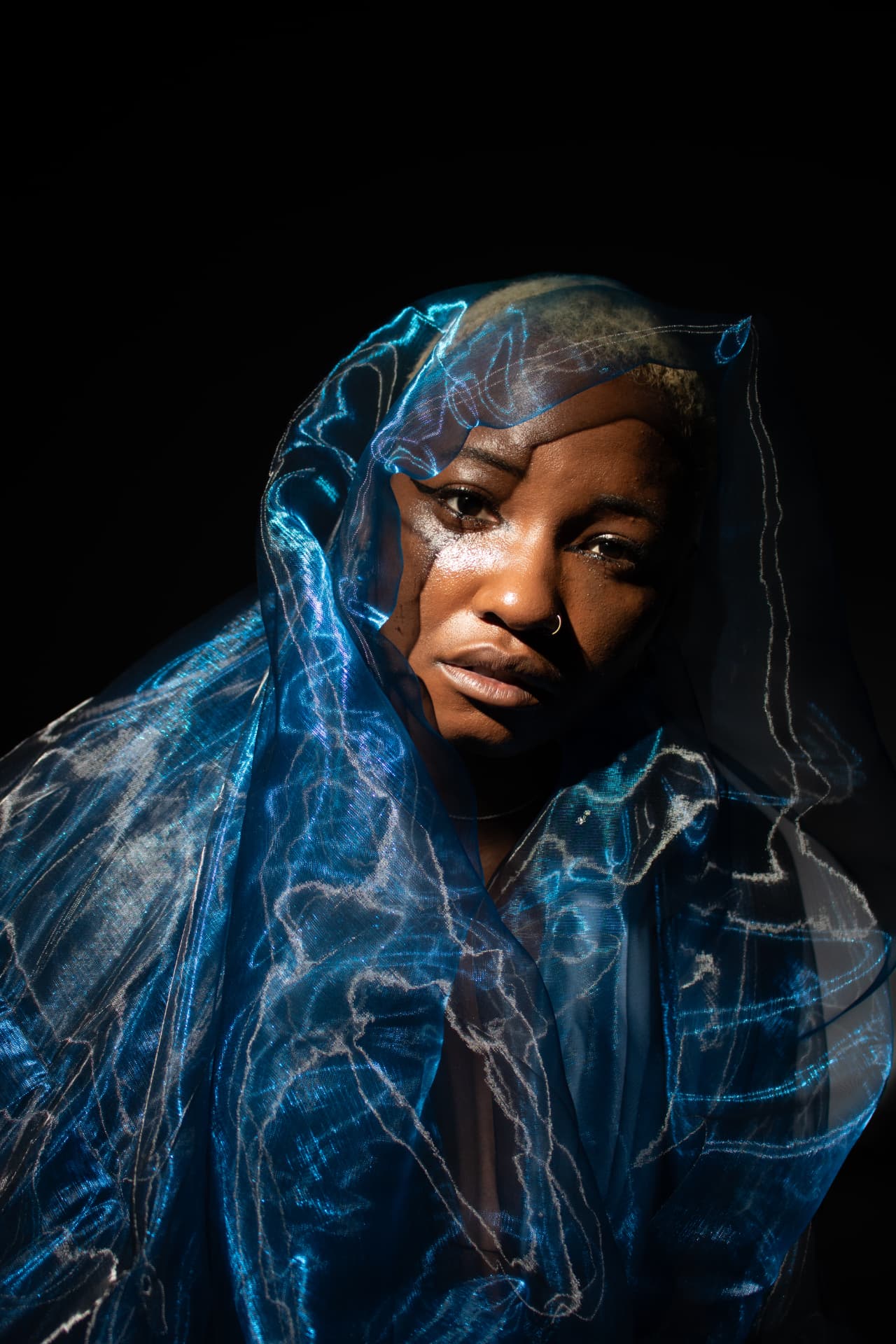 Portrait of a model hooded in blue organza